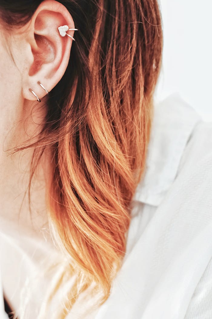 Close-up shot showcasing trendy ear piercings and a heart-shaped earring against a light backdrop.